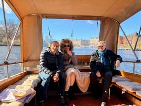 Three guests relax inside the cozy cabin of a boat, enjoying the scenic views of the water and surroundings — perfect for a leisurely day on the water.