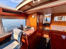 Interior view of a cozy boat cabin featuring a well-equipped helm and seating area, perfect for relaxing while enjoying the scenic waterfront.