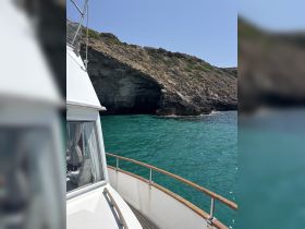 A scenic view from the deck of a boat, showcasing the rocky coastline and clear turquoise waters, perfect for exploring coastal landscapes.