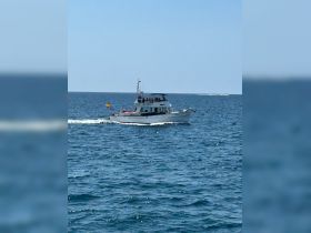 A lively boat cruising through the ocean, filled with guests enjoying the beautiful day on the water.