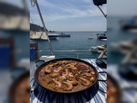 A delicious seafood paella served on a boat, showcasing the perfect culinary experience while enjoying the beautiful ocean view.