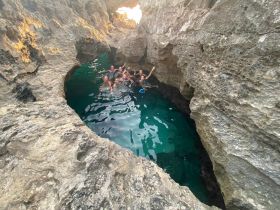 A lively group enjoys a refreshing swim in a scenic cave, surrounded by stunning rock formations — a perfect highlight of their boating adventure.