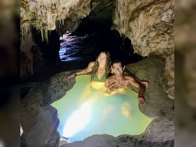 A couple enjoys a unique swimming experience in a cave, surrounded by stunning rock formations — perfect for adventurous getaways.