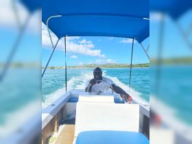 A cheerful captain navigates a boat through clear turquoise waters, showcasing the joy of on-water adventures.