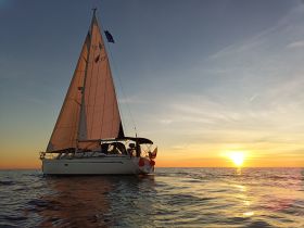 A stunning sailboat glides through calm waters at sunset, showcasing the beauty of sailing adventures on the open sea.