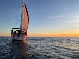 A stunning view of a sailboat navigating through calm waters at sunset, showcasing the beauty of sailing adventures.