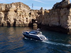 A sleek boat navigates along a stunning coastline, with a group enjoying the scenic views — perfect for adventure seekers exploring beautiful waterways.