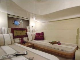 A cozy interior view of a boat cabin featuring comfortable seating and a porthole, perfect for relaxing during a voyage.