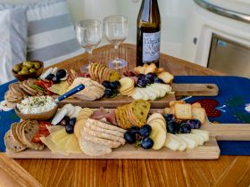 A beautifully arranged charcuterie board featuring a variety of cheeses, meats, and fruits, perfect for enjoying onboard with drinks.