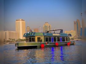A vibrant view of the 'Seven' boat navigating the waters against a backdrop of modern skyscrapers, showcasing the perfect blend of urban scenery and boating adventure.