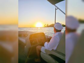A serene sunset view from the helm of a boat, with the captain enjoying the picturesque scenery — perfect for sunset cruises and relaxing moments on the water.