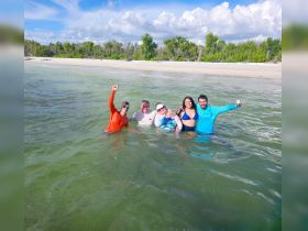 A joyful group of friends celebrates in the water, enjoying a fun day at the beach — perfect for creating lasting memories under the sun.