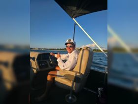 A cheerful captain gives a thumbs up while seated at the helm of a boat, showcasing the comfortable interior and inviting atmosphere for a day on the water.