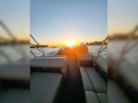 A serene sunset view from the interior of a boat, with a guest enjoying the peaceful atmosphere — perfect for unwinding after a day on the water.