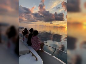 A group of friends enjoys a stunning sunset view from the bow of a boat, creating a serene atmosphere perfect for memorable moments on the water.