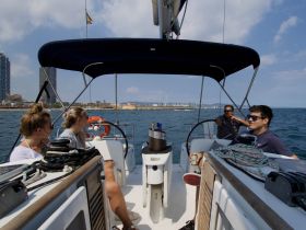 A group of friends enjoys a sailing experience in Barcelona, relaxing on the deck and taking in the scenic views of the coastline.