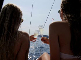 Two friends toast with champagne glasses aboard a yacht, enjoying a sunny day on the water — a perfect moment for celebrations and relaxation.