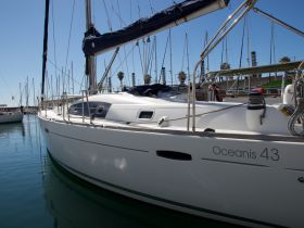 A close-up view of the Oceanis 43 yacht docked in a marina, showcasing its sleek design and tranquil surroundings.