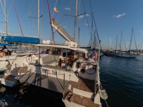 A catamaran docked in a marina, showcasing its spacious deck and modern design, perfect for leisurely outings on the water.