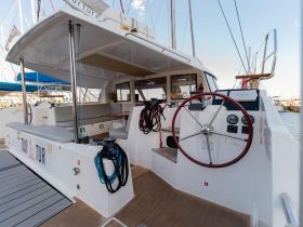 A well-equipped helm area inside a catamaran, featuring seating and navigation controls, perfect for comfortable sailing experiences.