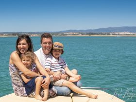 A joyful family enjoys a sunny day on a boat, capturing smiles and togetherness against a beautiful water backdrop — perfect for family outings and memorable adventures.