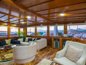 A cozy interior view of a boat's cabin featuring stylish seating and a helm area, perfect for relaxing and enjoying the journey on the water.