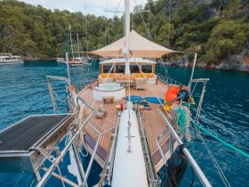 A beautifully designed interior of a yacht featuring a spacious lounge area with comfortable seating and a hot tub, perfect for relaxation while cruising in serene waters.