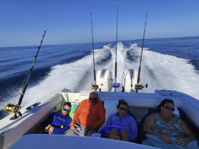 A group of friends relaxes on a fishing boat, enjoying the ocean breeze while the boat speeds through calm waters — a perfect day for fishing and camaraderie.