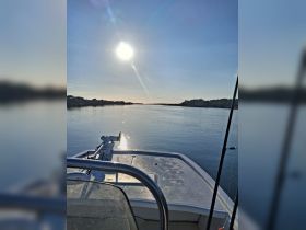 A serene view from the front of a boat, capturing the calm waters and a bright sun overhead, perfect for showcasing peaceful boating experiences.