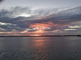 A stunning sunset reflects on the water, creating a picturesque scene perfect for romantic evenings or peaceful boat rides.