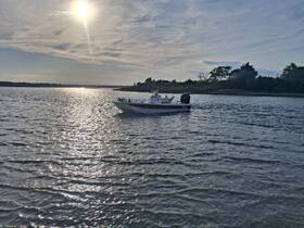 A sleek speedboat glides across shimmering waters under a bright sun, showcasing the beauty of a serene day on the water.
