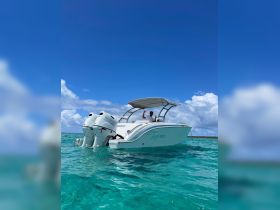 A person waves from the helm of a sleek boat cruising through crystal-clear waters, showcasing the perfect day for a boating adventure.