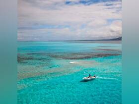 A stunning aerial view of a speedboat navigating through crystal-clear turquoise waters, showcasing the beauty of the ocean and the thrill of boating adventures.