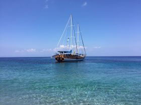 A beautiful sailboat anchored in crystal-clear waters under a bright blue sky, perfect for scenic coastal adventures.