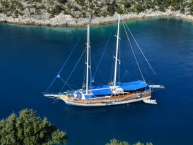 A stunning aerial view of a beautifully crafted sailboat anchored in serene blue waters, surrounded by lush greenery — perfect for exploring coastal destinations.