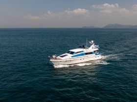 A luxurious yacht navigates through clear waters, showcasing an exciting day on the sea with guests enjoying the ride.