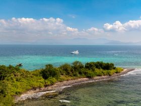 A stunning aerial view of a tranquil coastline with boats navigating the turquoise waters, showcasing the beauty of island adventures and scenic escapes.