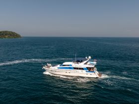A stunning aerial view of a sleek yacht cruising through clear waters, showcasing the beauty of maritime adventures.