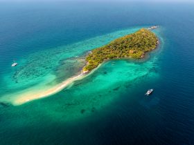 A stunning aerial view of a secluded island surrounded by crystal-clear waters, showcasing the beauty of tropical destinations and ideal for island hopping adventures.