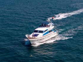 A luxurious yacht cruises through the ocean with a jet ski in tow, showcasing the thrill of water adventures and the beauty of the open sea.
