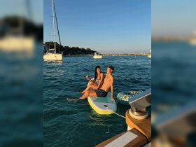 A couple enjoys a relaxing moment on a paddleboard, surrounded by beautiful waters and boats, perfect for summer adventures and fun on the water.
