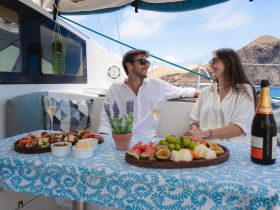 A couple enjoys a delightful spread of gourmet food and drinks on the deck of a yacht, perfect for a romantic getaway or special celebration on the water.