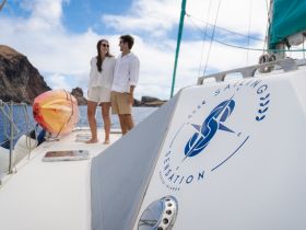 A couple enjoys a romantic moment aboard a sailing boat, surrounded by stunning coastal scenery — perfect for memorable sailing adventures.