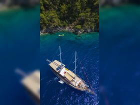A stunning aerial view of a yacht cruising through crystal-clear waters, surrounded by lush greenery — perfect for exploring secluded coves and enjoying the beauty of nature.