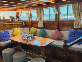 Cozy interior of a boat featuring comfortable seating and a wooden table, perfect for relaxing and enjoying the views while on the water.