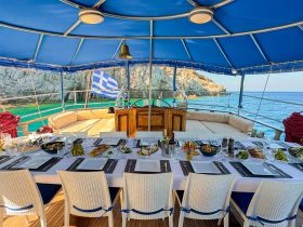 An elegantly set dining table aboard a boat, featuring a variety of gourmet dishes and drinks, perfect for a luxurious dining experience on the water.