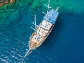 A stunning aerial view of a yacht cruising through crystal-clear waters, showcasing its elegant design and the vibrant marine environment.