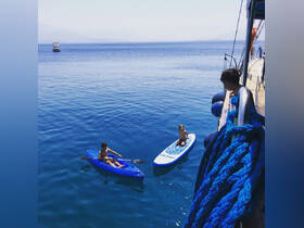 Two children enjoy a sunny day on the water, kayaking and paddleboarding in crystal-clear blue waters — a perfect scene for family fun and adventure.