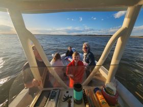 A joyful family enjoys their time on the water, with smiles all around as they take in the beautiful sunset views from their boat.