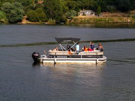 A lively group enjoys a river cruise on a pontoon boat, waving and celebrating under the sun — perfect for summer outings and family adventures.